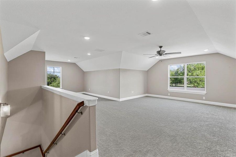 Additional living space with carpet flooring and vaulted ceiling