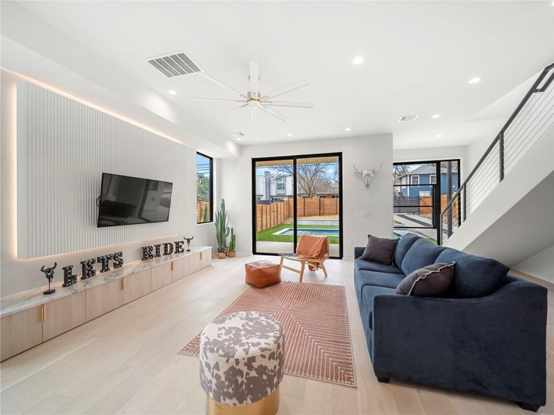Living area with light wood-type flooring, a ceiling fan, and recessed lighting