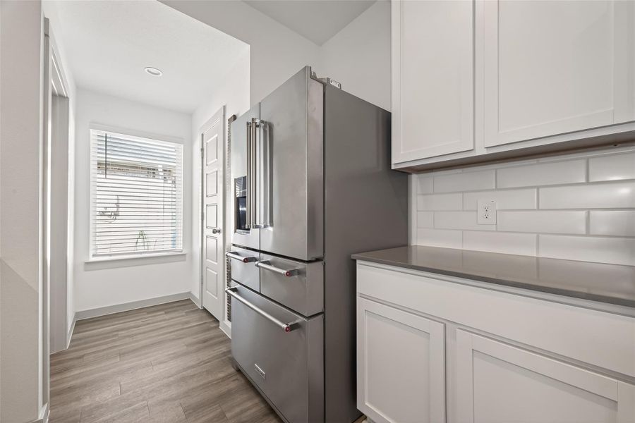 Past the fridge, utility room access to the left, pantry door to the right. Great window adds even more natural light to the space. Past the fridge, utility room access to the left, pantry door to the right. Great window adds even more natural light to the space.