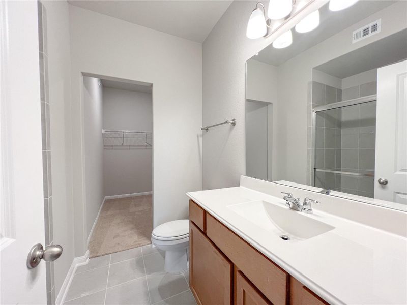 A well-appointed bathroom with a spacious vanity, large mirror, and adjacent walk-in closet. A well-appointed bathroom with a spacious vanity, large mirror, and adjacent walk-in closet.