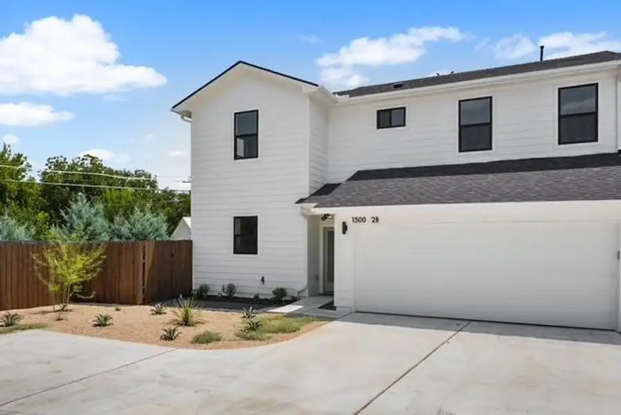 View of front of home with a garage, driveway, and a shingled roof