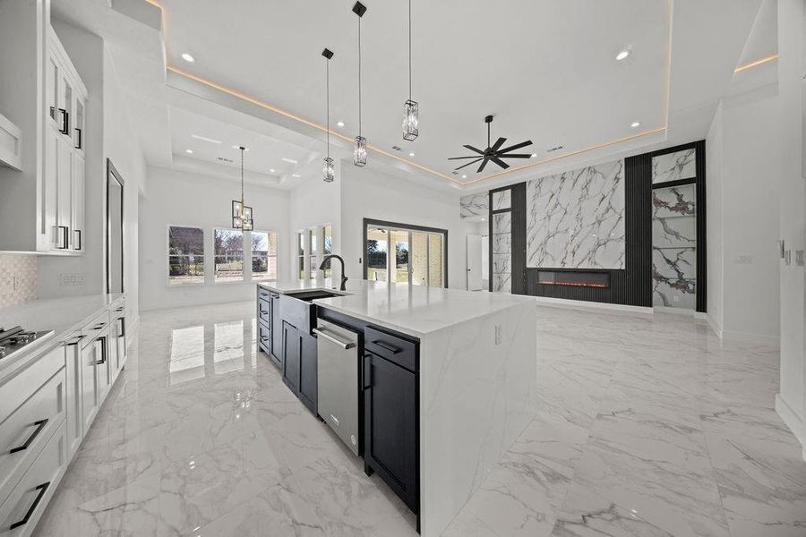 Kitchen featuring light stone counters, pendant lighting, a large island, open floor plan, and two tone cabinets