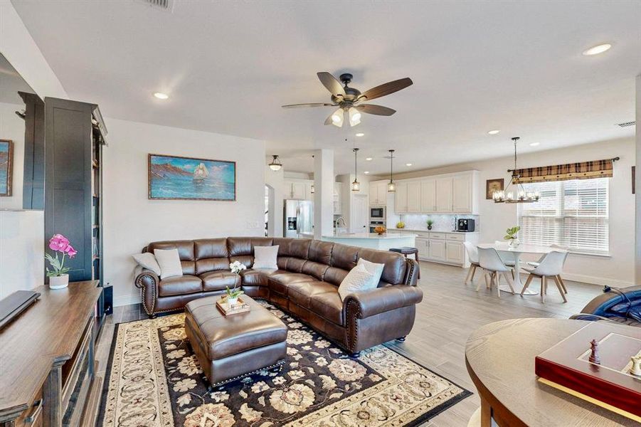 Living room with light wood-style flooring, ceiling fan, recessed lighting, and a chandelier