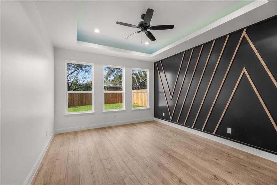 Spare room featuring light wood-type flooring, a tray ceiling, a ceiling fan, and recessed lighting