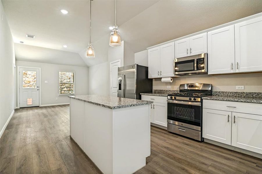 Kitchen featuring white shaker cabinetry, stainless steel appliances, granite countertops, and a central island Kitchen featuring white shaker cabinetry, stainless steel appliances, granite countertops, and a central island
