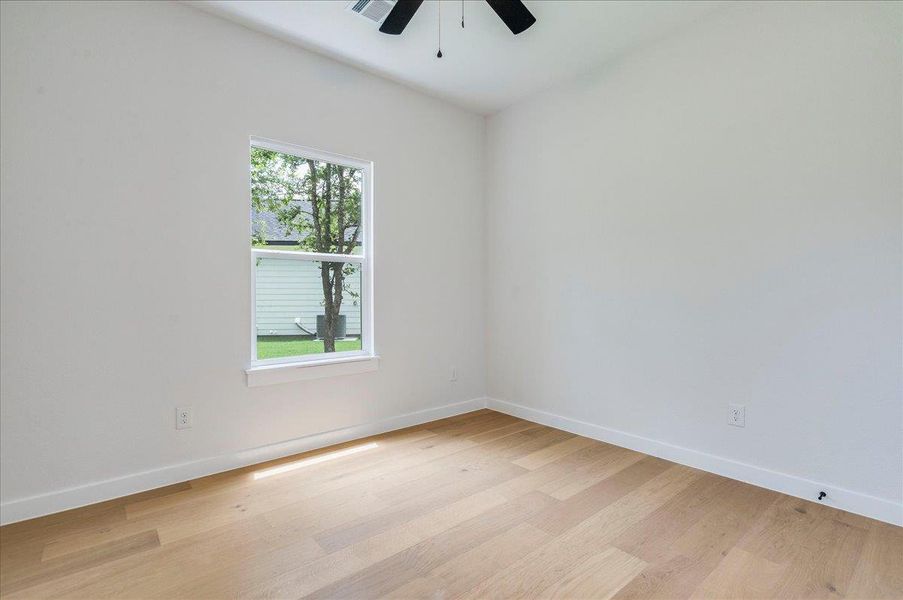 Hardwood flooring extends throughout this naturally illuminated, unfurnished third bedroom, perfect for personalizing your space.