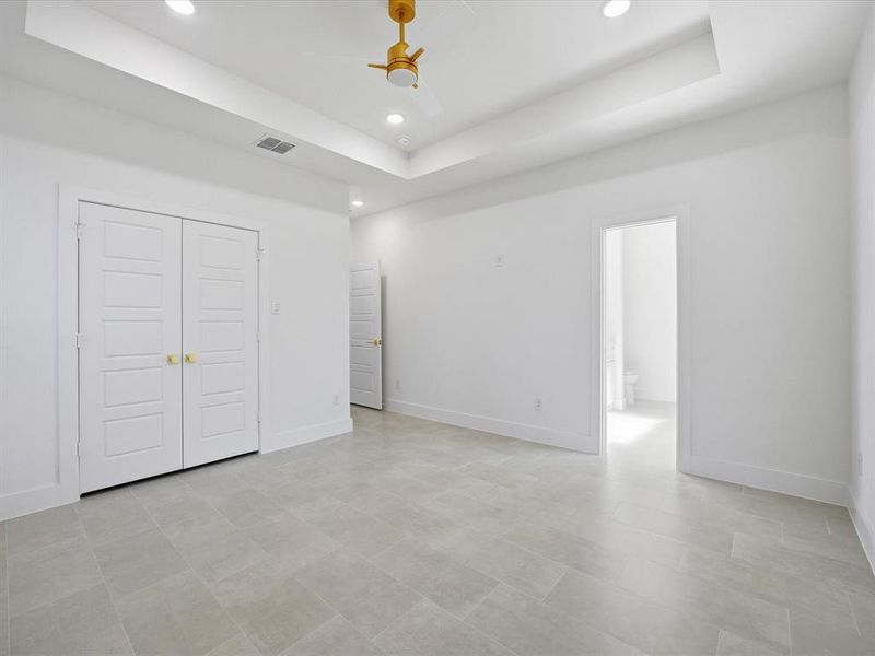 Unfurnished bedroom with a tray ceiling, a ceiling fan, a closet, and recessed lighting