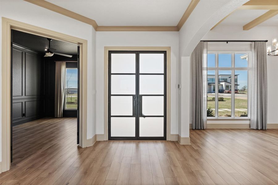 Doorway featuring baseboards, arched walkways, ornamental molding, and light wood finished floors