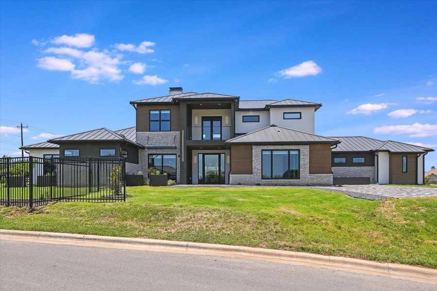 View of front of home with a standing seam roof, a metal roof, balcony, chimney, and brick and wood siding View of front of home with a standing seam roof, a metal roof, balcony, chimney, and brick and wood siding