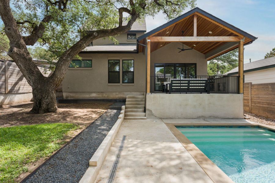 Back of the home with a covered patio and a beautiful live oak tree.