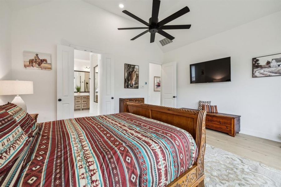 Bedroom with lofted ceiling, wood finished floors, connected bathroom, ceiling fan, and recessed lighting