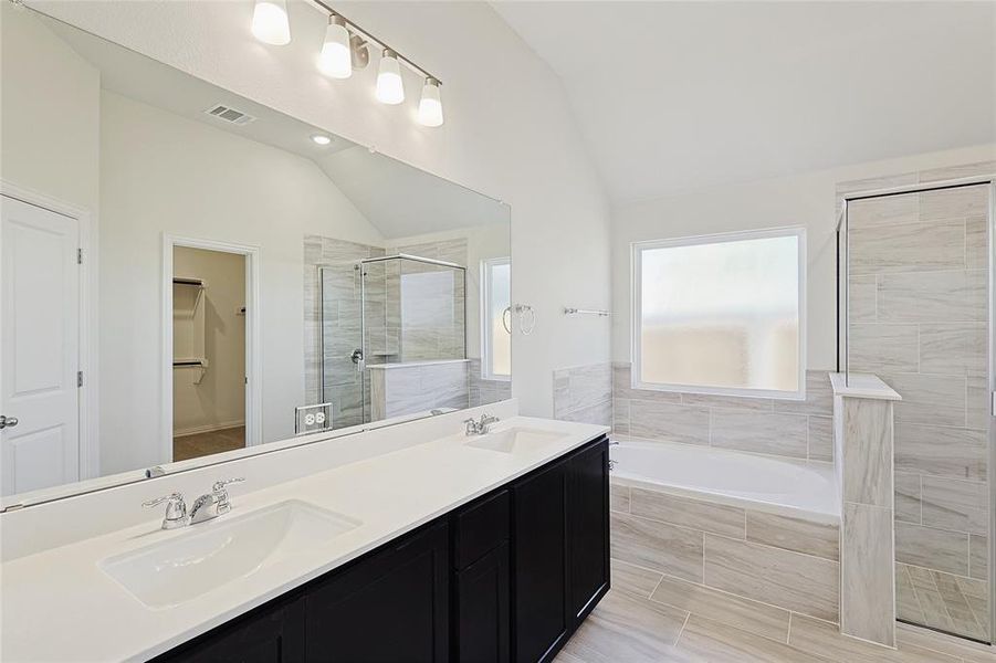 Bathroom with vanity, plus walk in shower, and vaulted ceiling