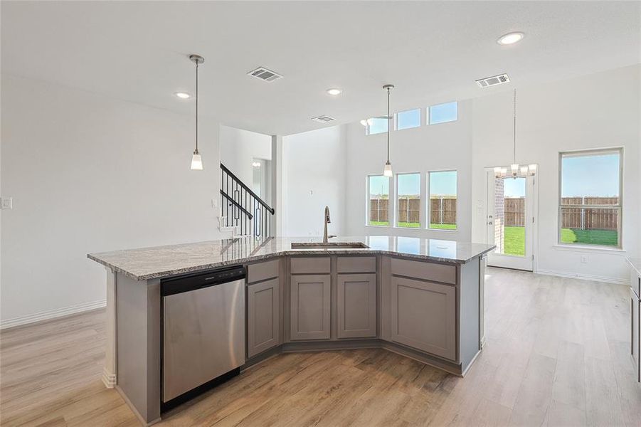 Kitchen with dishwasher, sink, a center island with sink, and light wood-type flooring