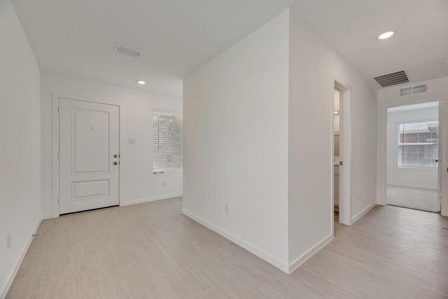 Hall with light wood finished floors, recessed lighting, and plenty of natural light