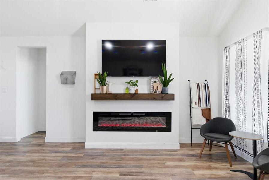 Living area featuring a glass covered fireplace and light wood-style floors Living area featuring a glass covered fireplace and light wood-style floors