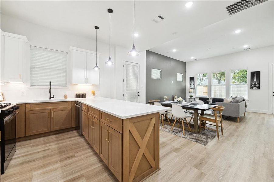 View of the first-floor living area from the kitchen. The natural wood cabinetry is thoughtfully complemented by white Calacatta quartz countertops and gold hardware.