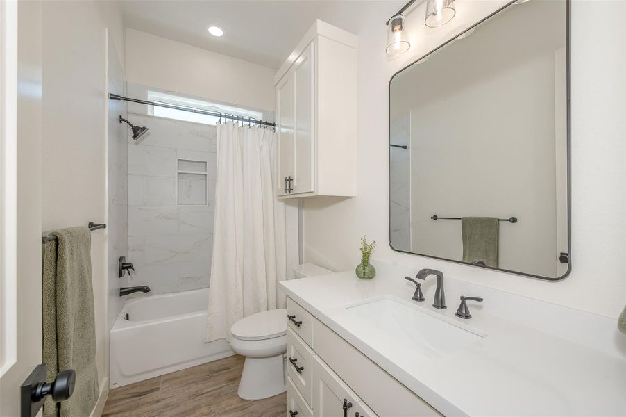 Full bath featuring shower / tub combo with curtain, vanity, and light wood-type flooring