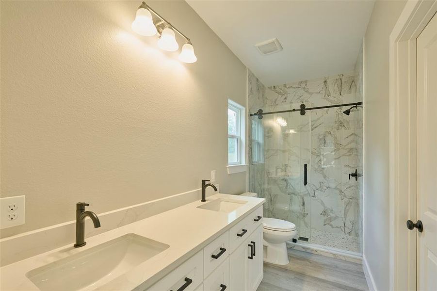 Primary bathrm features custom shower, dual sinks, quartz counters & a new mirror will be installed.