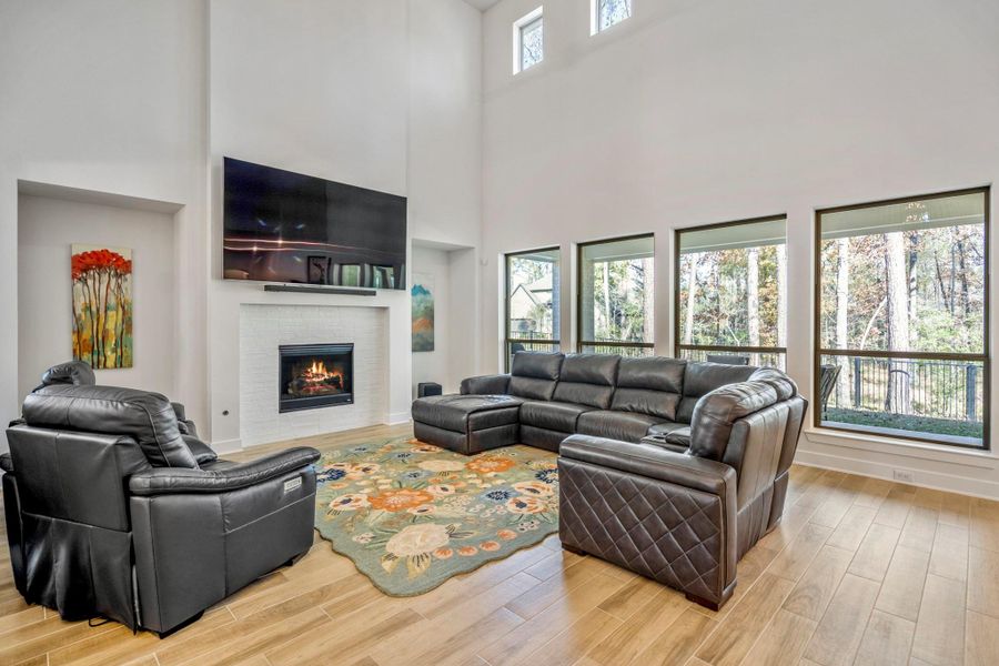 A cozy living space with a fireplace complemented by stylish flooring and towering ceilings!