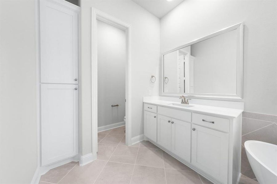 Primary bathroom featuring a freestanding soaking tub, vanity, and tile patterned floors