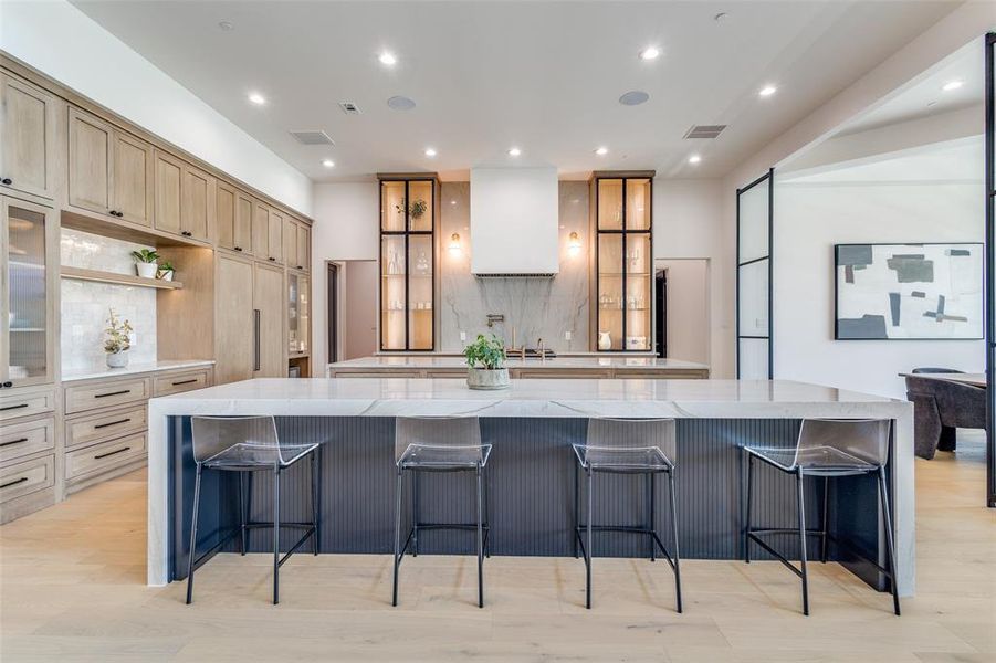 Kitchen featuring light stone counters, a kitchen bar, a large island, and light wood-type flooring