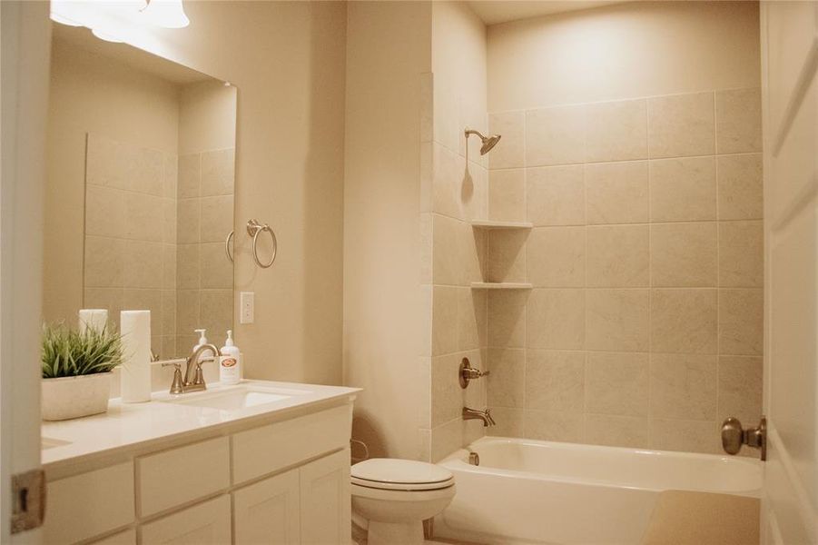 Full bathroom with tiled shower / bath, vanity, and toilet