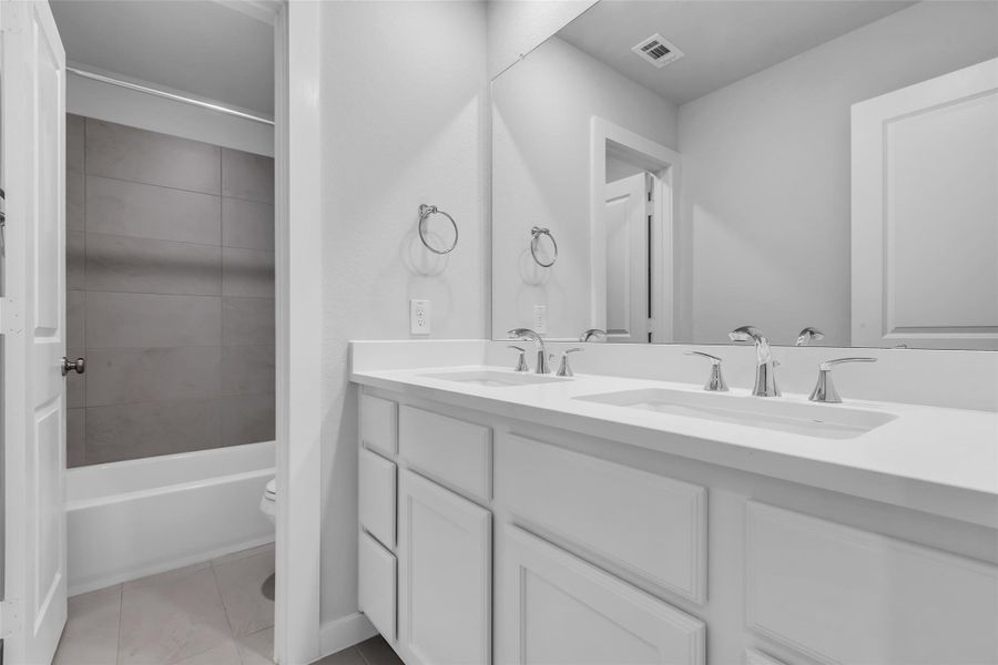 Functional and elegant, the upstairs guest bath offers double sinks and a fully tiled tub surround.