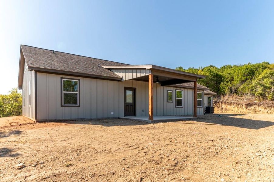 View of front of house featuring a patio, a shingled roof, board and batten siding, and a ceiling fan