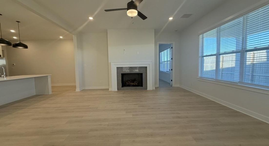 Unfurnished living room with a ceiling fan, light wood-type flooring, recessed lighting, and a tile fireplace