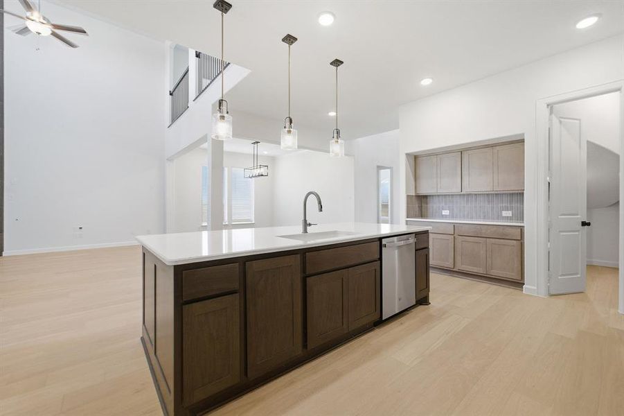 Modern kitchen island featuring dark wood cabinetry, a white countertop, and an integrated stainless steel dishwasher
