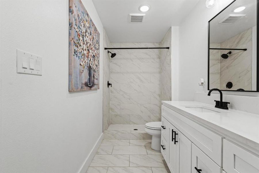 Full bath featuring vanity, a marble finish shower, and light marble finish flooring