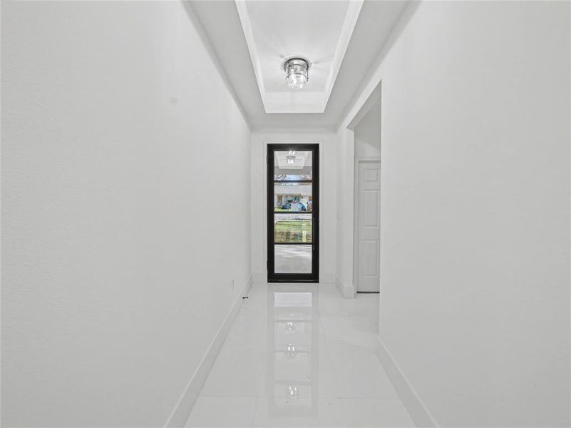 Corridor with baseboards and a tray ceiling