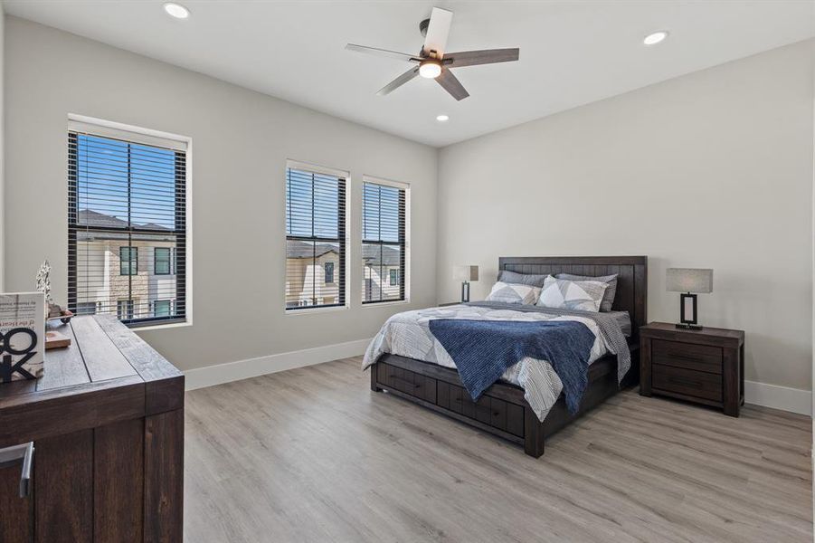 Bedroom featuring light wood-style flooring, multiple windows, ceiling fan, and recessed lighting