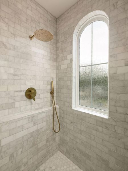 Rainfall shower head and handheld sprayer complete this elegant, tiled primary bathroom shower.