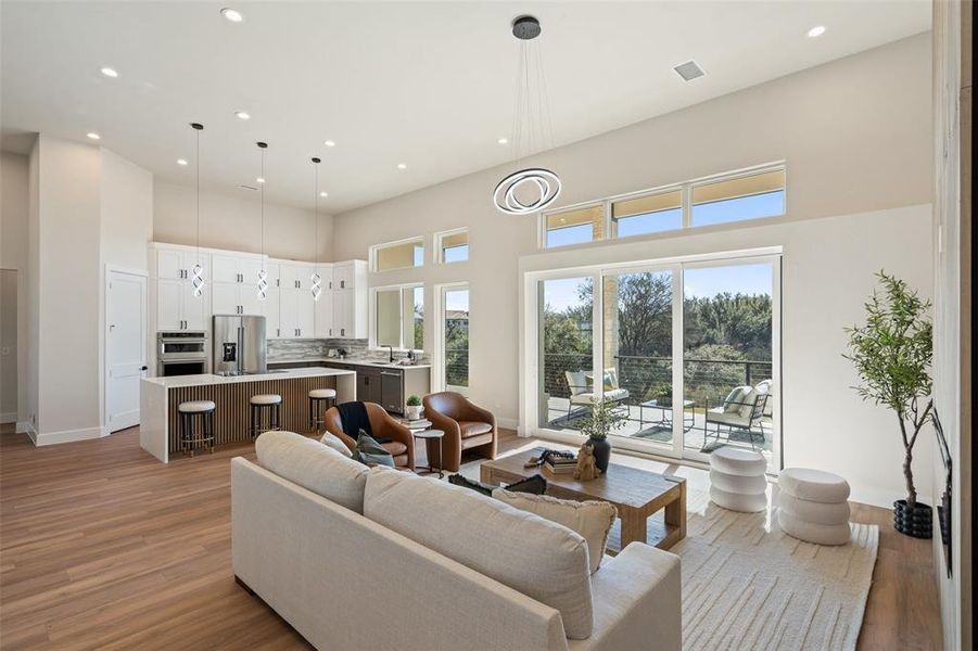 Living room featuring a towering ceiling, plenty of natural light, light wood-style flooring, and recessed lighting Living room featuring a towering ceiling, plenty of natural light, light wood-style flooring, and recessed lighting