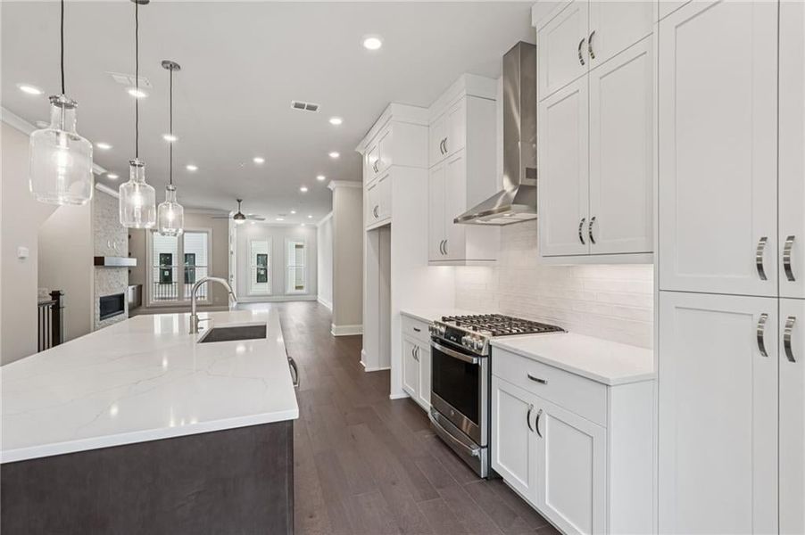 Kitchen with a large island, gas stove, a large fireplace, dark wood-style flooring, and open floor plan