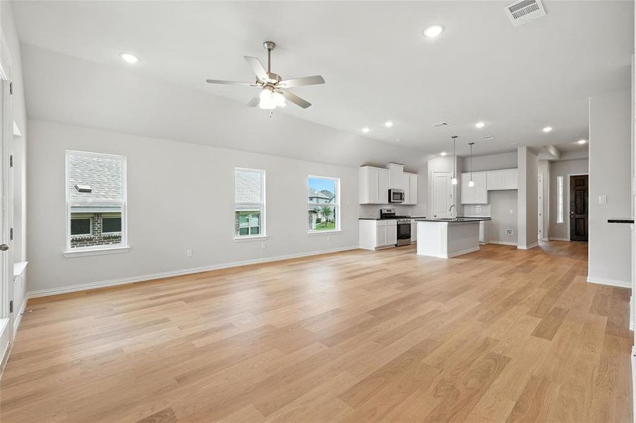 Unfurnished living room featuring a ceiling fan, light wood-style flooring, recessed lighting, and vaulted ceiling