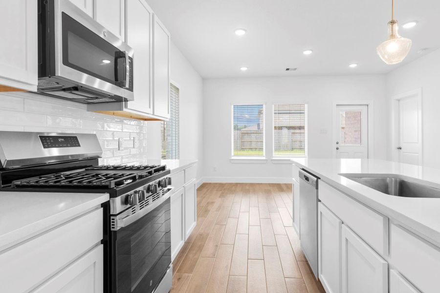 Sleek and functional kitchen layout with stainless steel 5 burner gas range, and cabinets that will surround you!