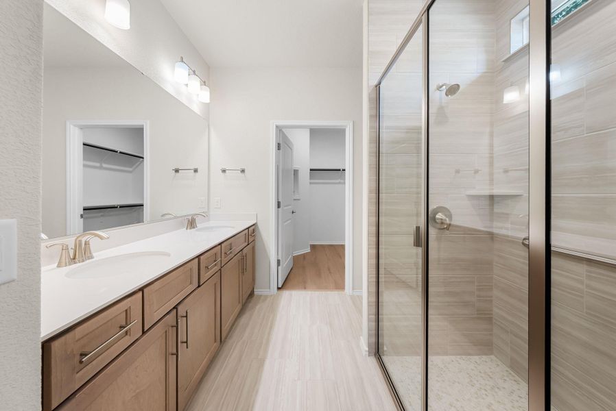 Dual vanity with a spacious countertop complements the modern glass-enclosed shower, creating a refreshed bathing space. Dual vanity with a spacious countertop complements the modern glass-enclosed shower, creating a refreshed bathing space.