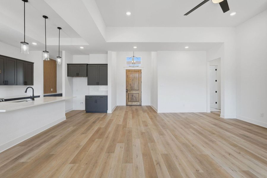 Spacious open-concept living area featuring luxury vinyl plank flooring, high ceilings, and an electric fireplace that anchors the space