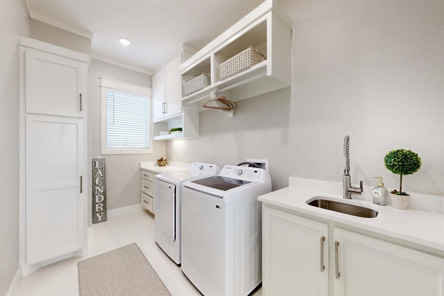 This light and bright utility room has everything you need. A sink, a place to hang clothes straight from the dryer, a broom closet, folding space and extra cabinets for cleaning supplies. The builder thought of everything.