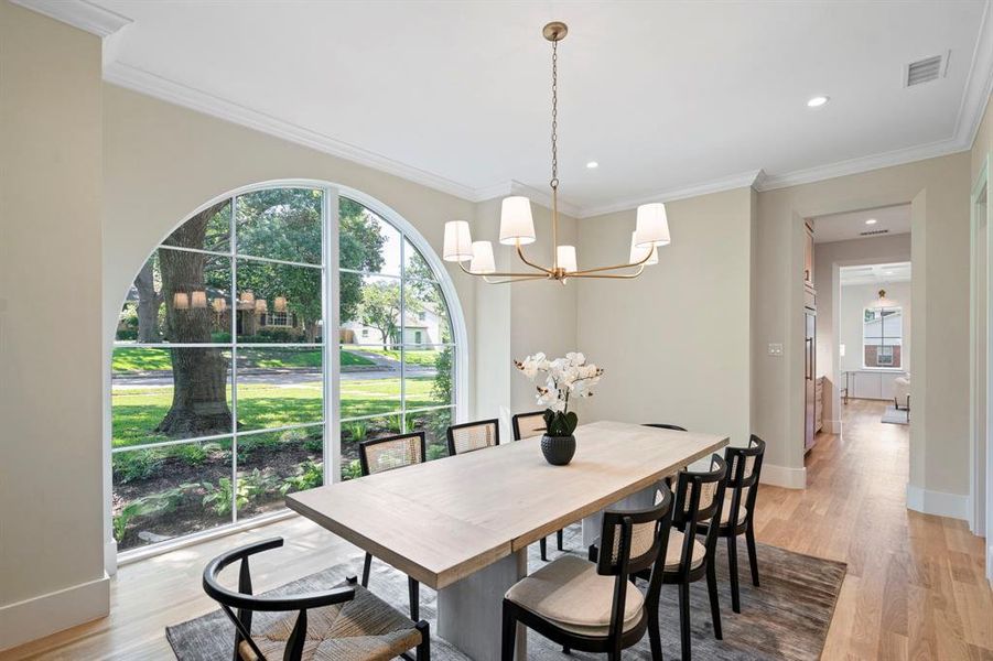 Dining area with wood-type flooring, a chandelier, and ornamental molding