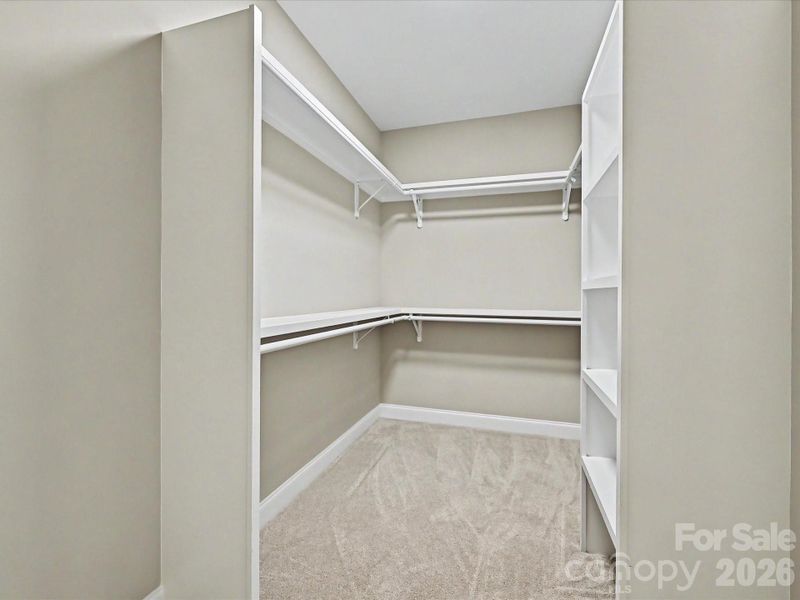 Spacious walk-in closet provides abundant storage with built-in shelving and convenient dual hanging space.