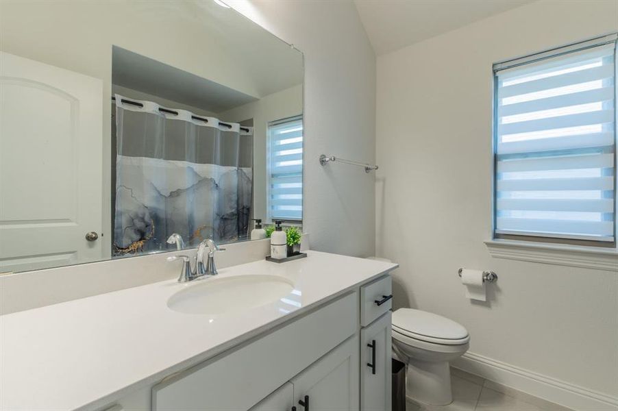 Bathroom featuring an integrated sink with a chrome faucet, white cabinetry with black hardware, and a large mirror