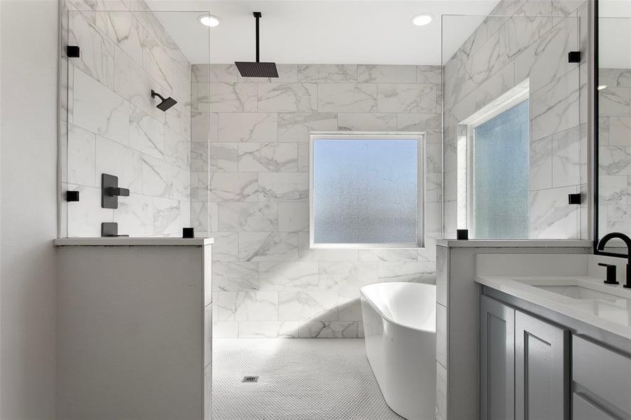 Full bathroom featuring vanity, a freestanding bath, a marble finish shower, and tile walls