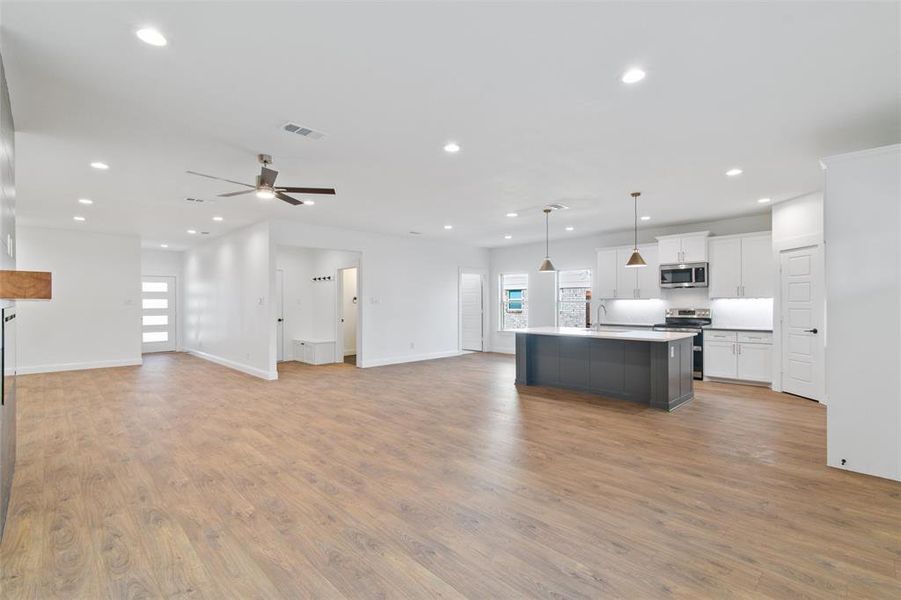 Kitchen with white cabinetry, ceiling fan, hanging light fixtures, a center island with sink, and appliances with stainless steel finishes