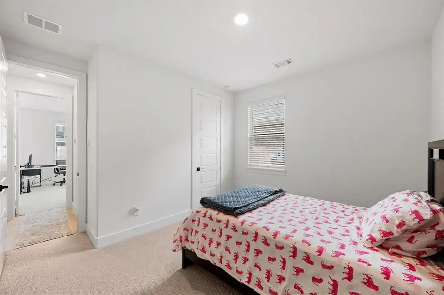 Carpeted room featuring a single window with blinds, recessed lighting, and a five-panel interior door with matte black hardware Carpeted room featuring a single window with blinds, recessed lighting, and a five-panel interior door with matte black hardware