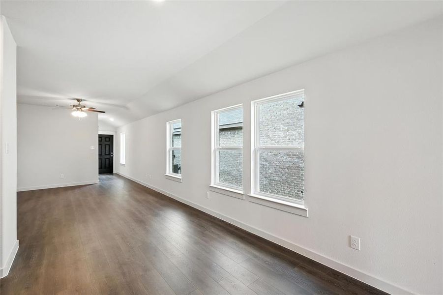 Unfurnished living room featuring ceiling fan, dark wood-style flooring, and vaulted ceiling Unfurnished living room featuring ceiling fan, dark wood-style flooring, and vaulted ceiling