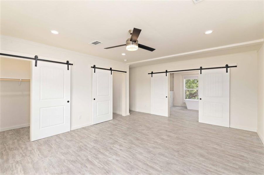 Spacious room featuring wood-finish flooring, recessed lighting, and a ceiling fan with integrated lighting