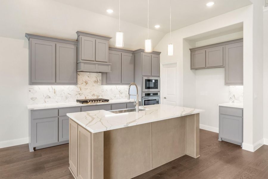 Kitchen with gray cabinets, marble backsplash, center island with sink, and stainless steel appliances on dark hardwood floors Kitchen with gray cabinets, marble backsplash, center island with sink, and stainless steel appliances on dark hardwood floors